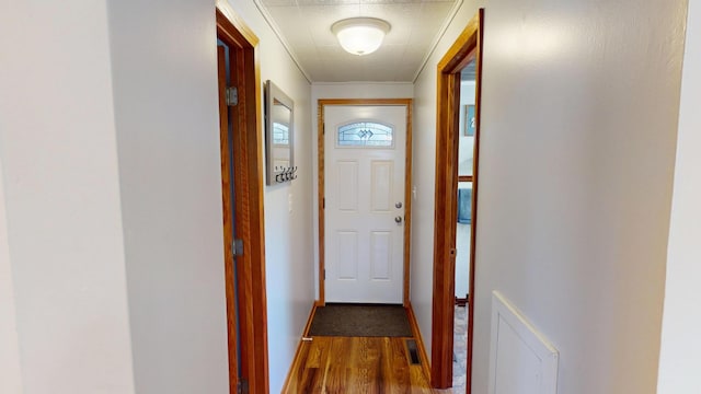 doorway to outside featuring wood finished floors, crown molding, and baseboards