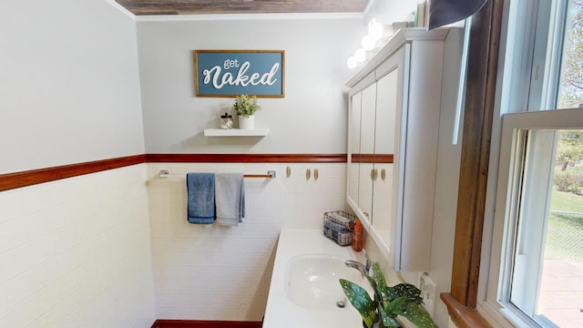 bathroom featuring tile walls, a sink, and ornamental molding
