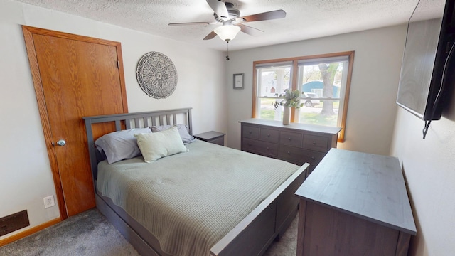 bedroom with dark carpet, a textured ceiling, and a ceiling fan