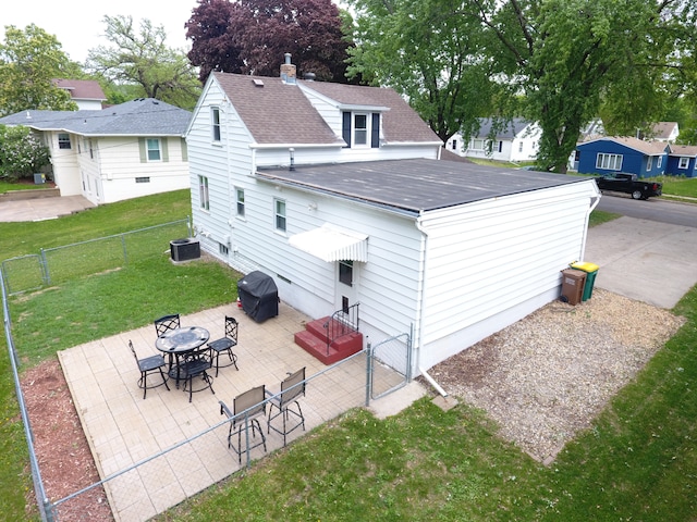 rear view of property with a gate, a patio, and a shingled roof