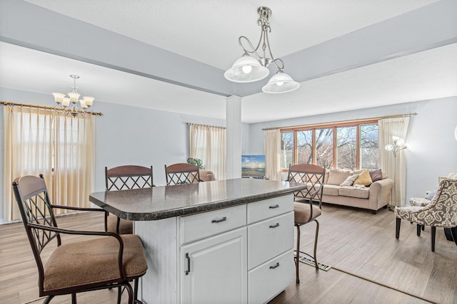 12420 Chippewa Ln, Burnsville, MN 55337 - kitchen with dark countertops, light wood-style floors, white cabinets, a kitchen bar, and plenty of natural light