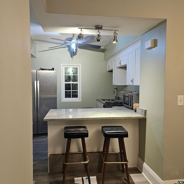 2407 4th St, Minneapolis, MN 55411 - kitchen featuring appliances with stainless steel finishes, ceiling fan, a peninsula, white cabinetry, and a breakfast bar area