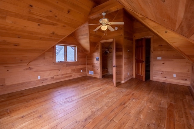additional living space with hardwood / wood-style floors, wooden walls, wooden ceiling, vaulted ceiling, and a ceiling fan
