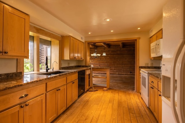 kitchen featuring white appliances, a sink, light wood-style floors, dark stone counters, and recessed lighting