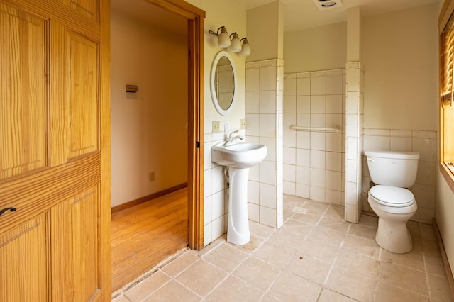 bathroom with tile walls, toilet, wainscoting, and tile patterned flooring