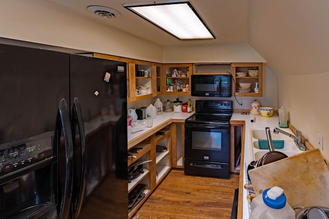 kitchen featuring black appliances, open shelves, light wood-style flooring, light countertops, and a sink