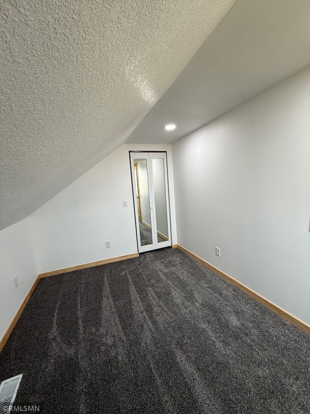 1616 130th Ave, Erin Prairie Twp, WI 54017 - additional living space with baseboards, dark carpet, lofted ceiling, and a textured ceiling