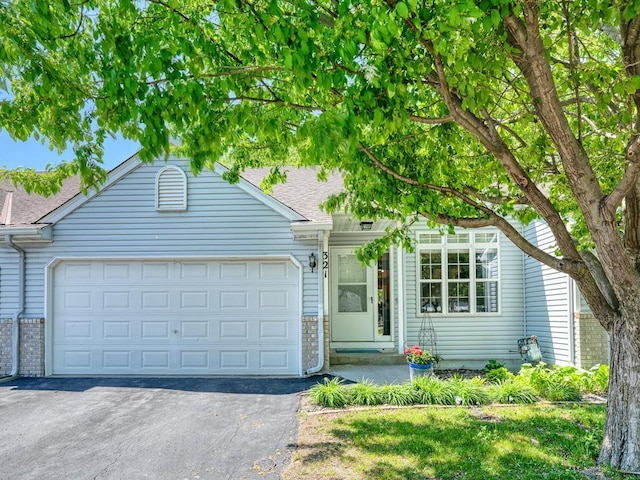 view of front of property with driveway, an attached garage, a shingled roof, and brick siding