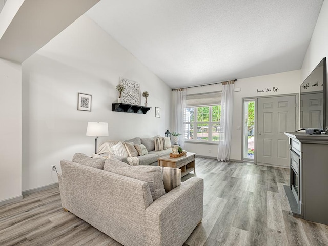 living room featuring light wood finished floors, vaulted ceiling, and baseboards