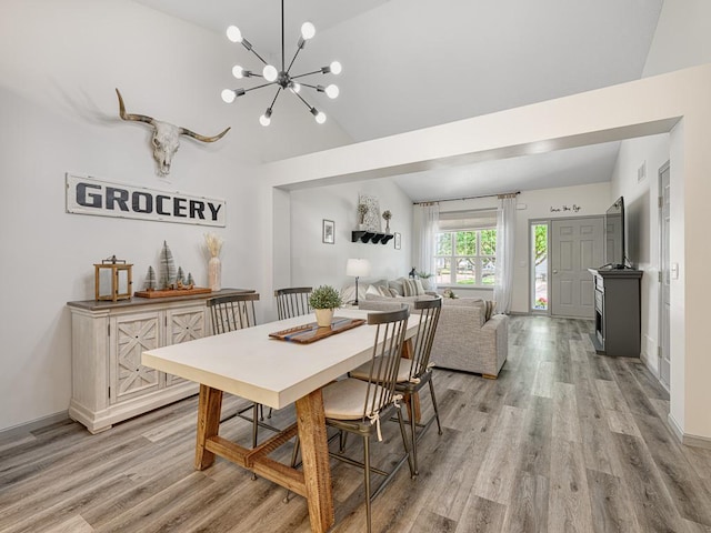 dining space with lofted ceiling, light wood-style flooring, a chandelier, and baseboards