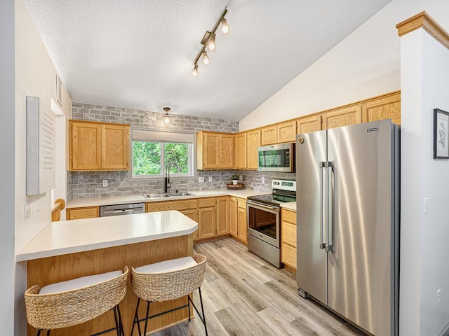 kitchen featuring stainless steel appliances, a sink, light countertops, decorative backsplash, and a textured ceiling