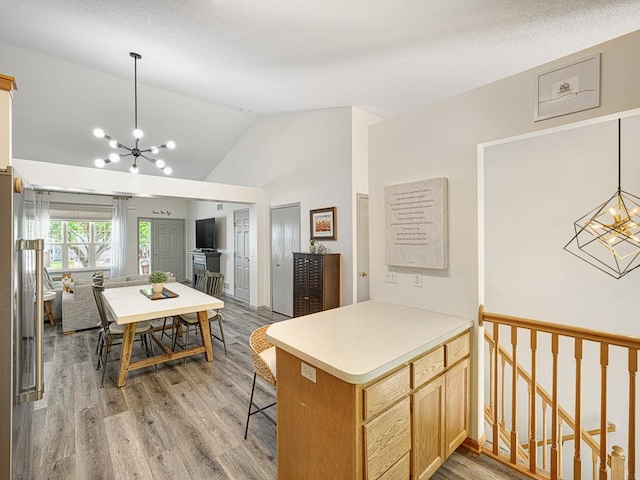 kitchen featuring a chandelier, vaulted ceiling, light wood-style floors, and light countertops
