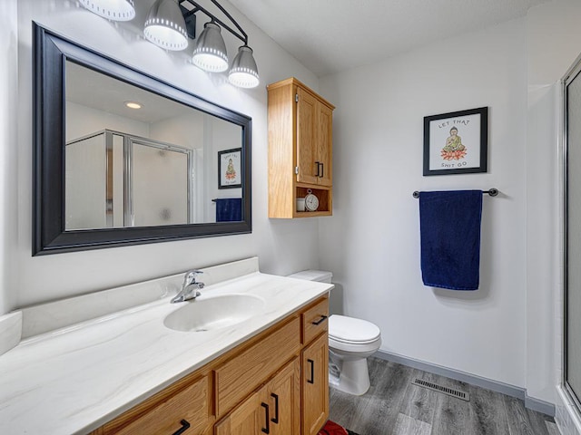 full bath with wood finished floors, a stall shower, vanity, and toilet