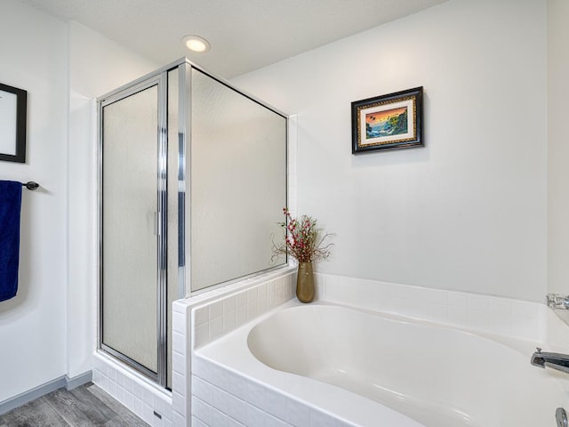 bathroom featuring a shower stall, a bath, and wood finished floors