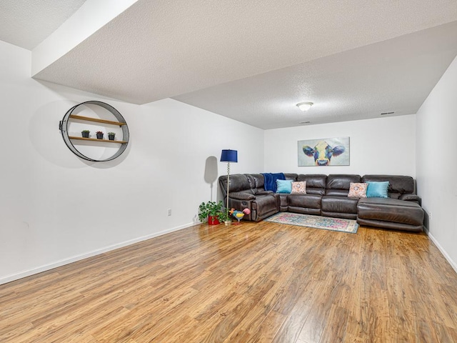 living area with light wood-style flooring, a textured ceiling, and baseboards