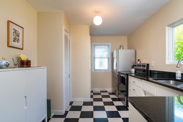 kitchen with electric range, a sink, dark floors, dark countertops, and white cabinetry