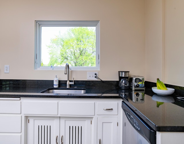 kitchen with a sink, dishwasher, white cabinets, and dark stone countertops