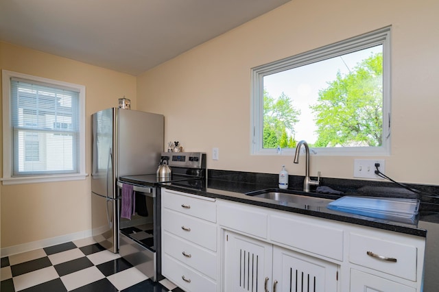 kitchen with appliances with stainless steel finishes, a sink, tile patterned floors, and plenty of natural light