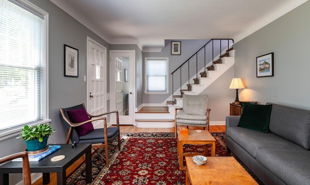 living area with stairway, wood finished floors, and baseboards