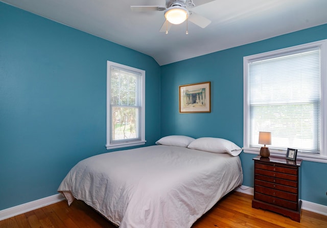 bedroom featuring baseboards, wood finished floors, a ceiling fan, and lofted ceiling