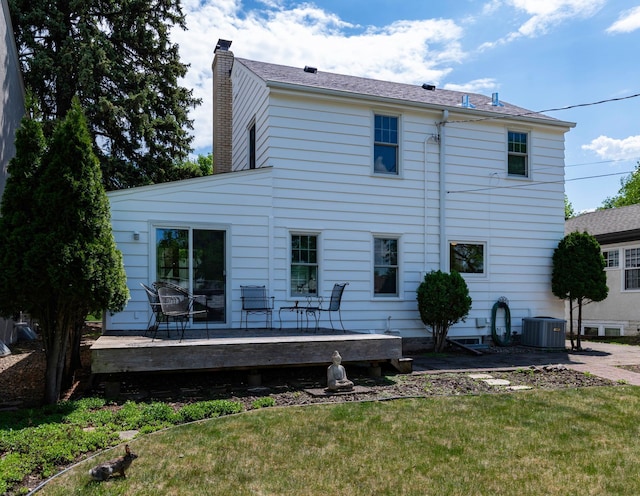 back of property featuring a deck, a chimney, a yard, and central AC