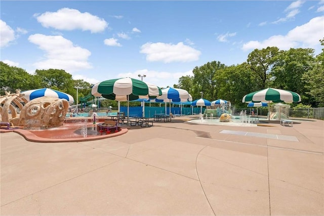 community pool with a water play area, fence, and a patio
