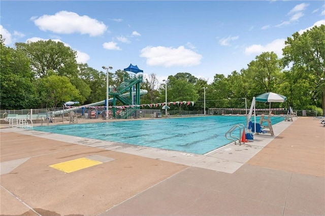 view of swimming pool with fence and view of wooded area