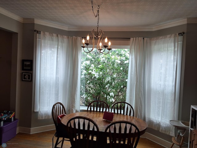 dining space featuring wood finished floors, baseboards, a chandelier, ornamental molding, and a textured ceiling