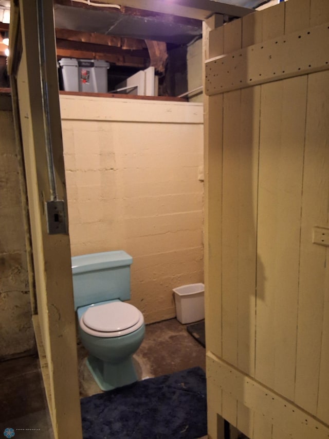 bathroom with toilet and unfinished concrete flooring