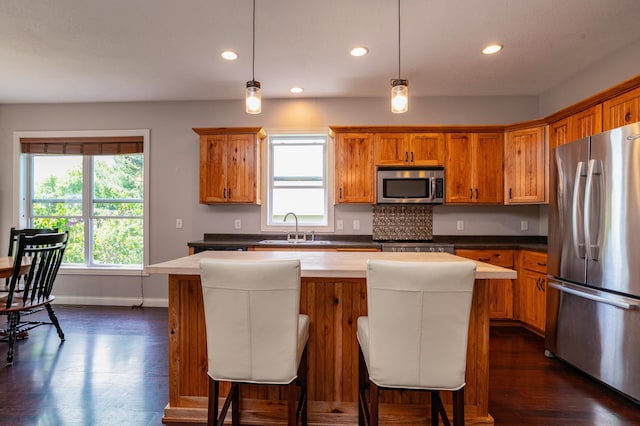 721 Quail Pkwy, Watertown, MN 55388 - kitchen with stainless steel appliances, a sink, brown cabinetry, a kitchen island, and recessed lighting