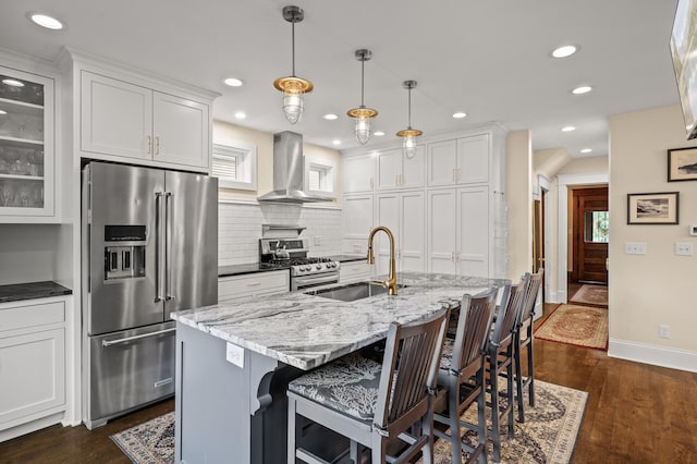 kitchen with stainless steel appliances, wall chimney exhaust hood, a sink, tasteful backsplash, and white cabinetry