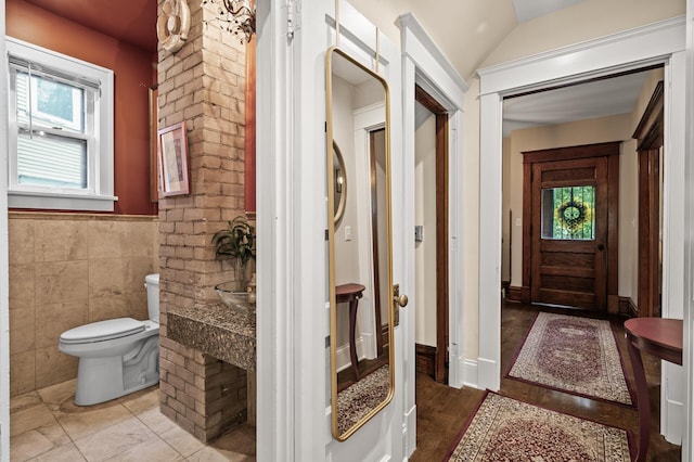 bathroom featuring toilet, wainscoting, and tile walls