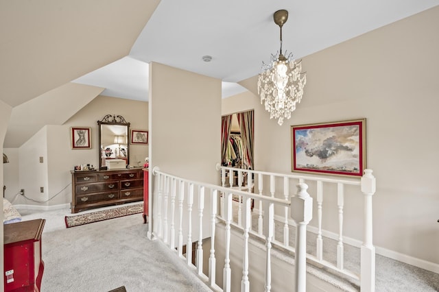 corridor featuring an upstairs landing, carpet, a chandelier, lofted ceiling, and baseboards