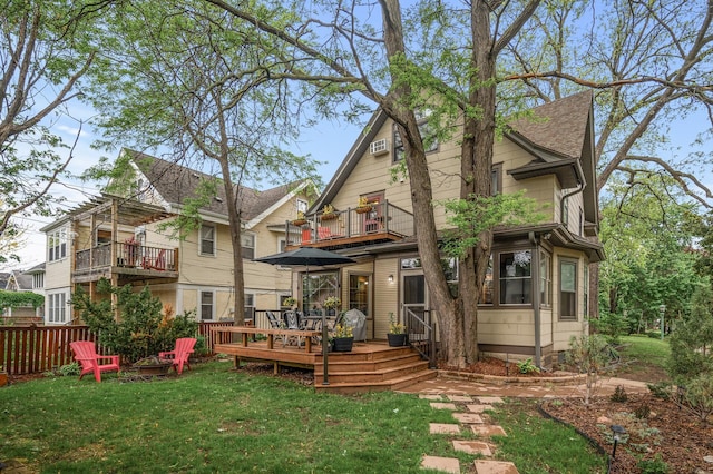 rear view of property featuring a balcony, a yard, a deck, and a shingled roof