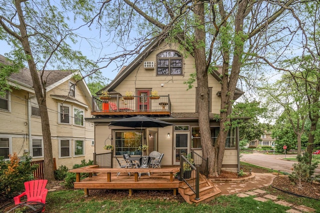rear view of property featuring a balcony, a wooden deck, outdoor dining area, and a wall mounted air conditioner
