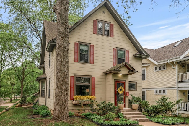 traditional style home featuring roof with shingles