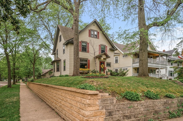 victorian home with a front yard, a balcony, and roof with shingles