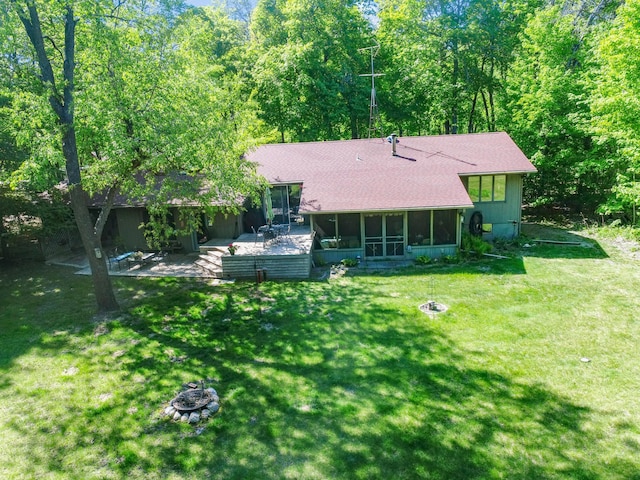 2536 Sandhill Ln NE, Carlos Twp, MN 56308 - rear view of house with a sunroom, a lawn, roof with shingles, and an outdoor fire pit