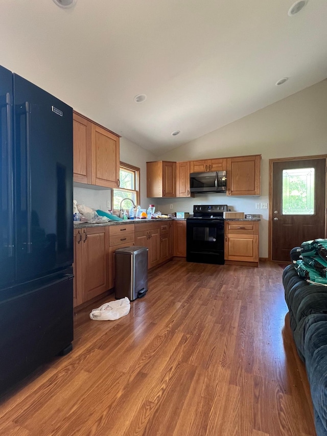 34373 State Highway 7, Foster Twp, MN 56225 - kitchen with black appliances, lofted ceiling, light wood-type flooring, and brown cabinetry