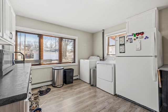 4959 5th St NE, Columbia Heights, MN 55421 - washroom with a baseboard radiator, cabinet space, washing machine and dryer, and light wood-style flooring