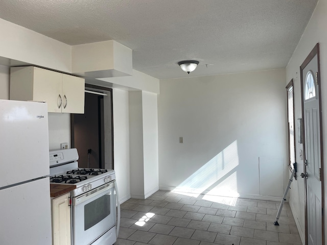 kitchen featuring white appliances, white cabinetry, a textured ceiling, baseboards, and light tile patterned flooring