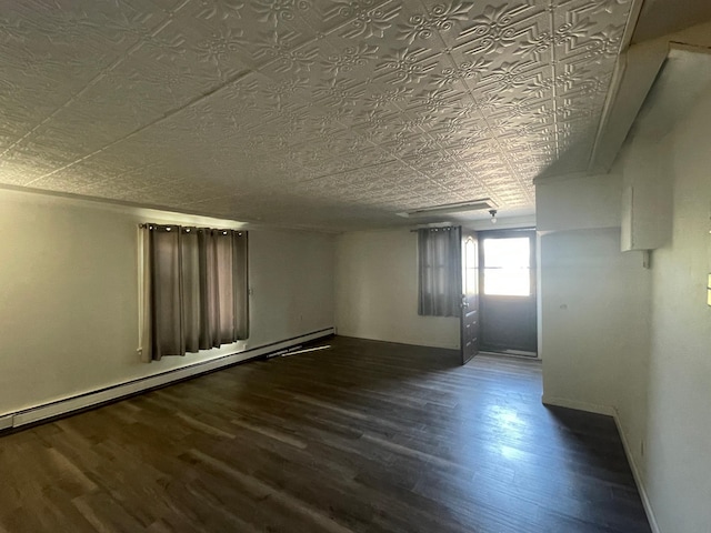 spare room with baseboard heating, wood finished floors, and an ornate ceiling