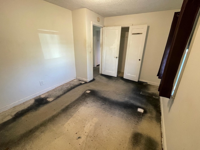 unfurnished bedroom featuring a textured ceiling, baseboards, and dark carpet