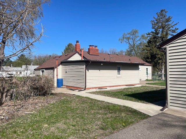 rear view of house with a chimney and a lawn