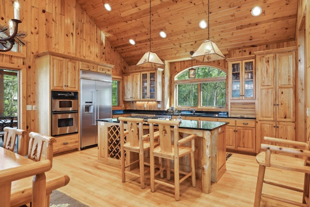 41849 Birchwood Dr, Emily, MN 56447 - kitchen featuring appliances with stainless steel finishes, a kitchen island, a sink, a breakfast bar, and glass insert cabinets