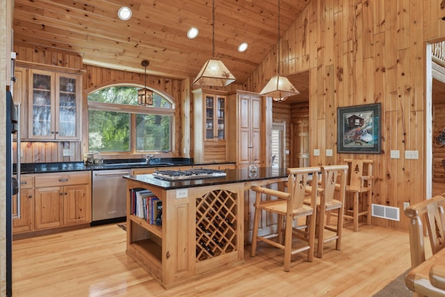 41849 Birchwood Dr, Emily, MN 56447 - kitchen with appliances with stainless steel finishes, wood walls, a breakfast bar area, light wood finished floors, and a kitchen island