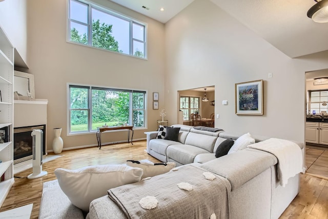 18046 Zodiac St NE, Columbus, MN 55025 - living area featuring a towering ceiling, plenty of natural light, light wood-type flooring, a fireplace with flush hearth, and baseboards