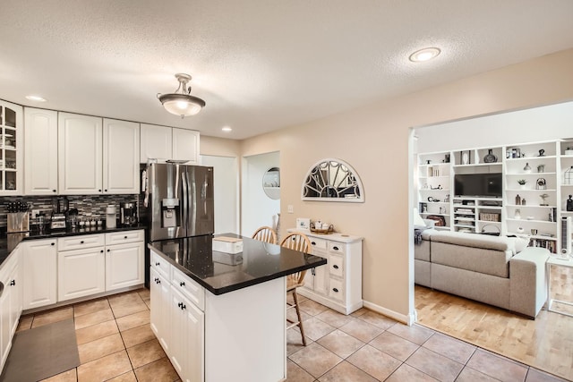 18046 Zodiac St NE, Columbus, MN 55025 - kitchen featuring stainless steel fridge, light tile patterned flooring, glass insert cabinets, a textured ceiling, and dark countertops
