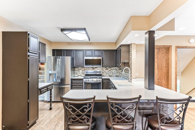 14308 Park Ave, Burnsville, MN 55337 - kitchen featuring stainless steel appliances, a sink, a peninsula, light wood-type flooring, and recessed lighting