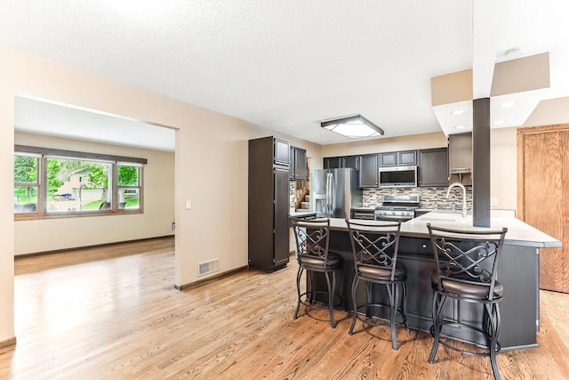 14308 Park Ave, Burnsville, MN 55337 - kitchen featuring appliances with stainless steel finishes, a peninsula, light wood-style floors, and backsplash